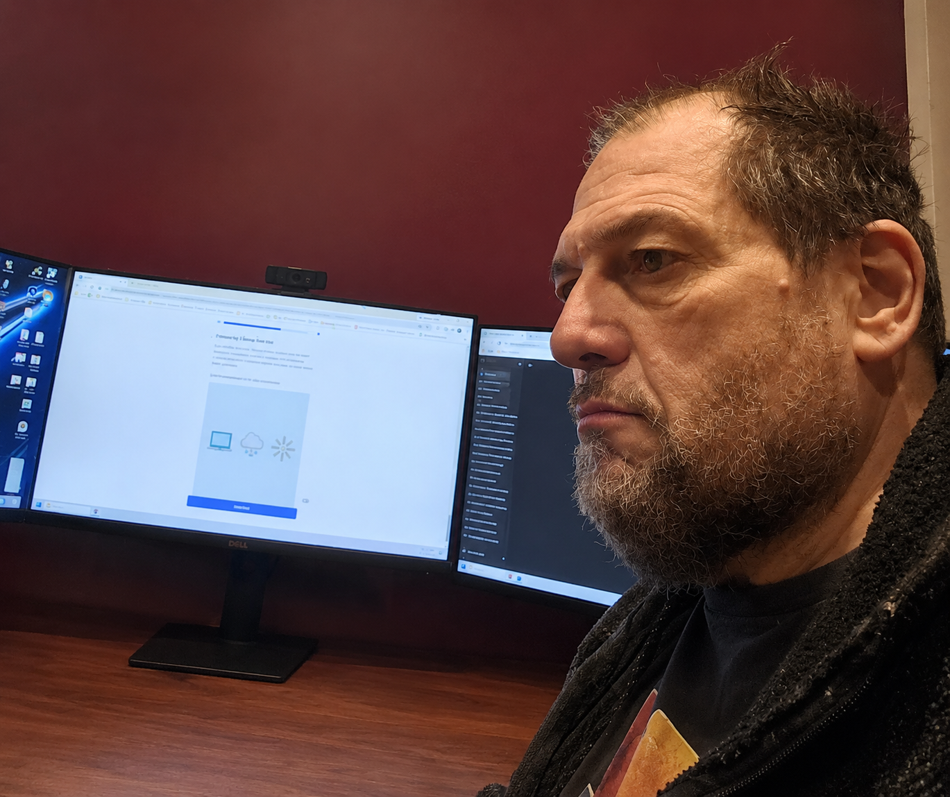 Tom Backus working thoughtfully at a multi-monitor workstation